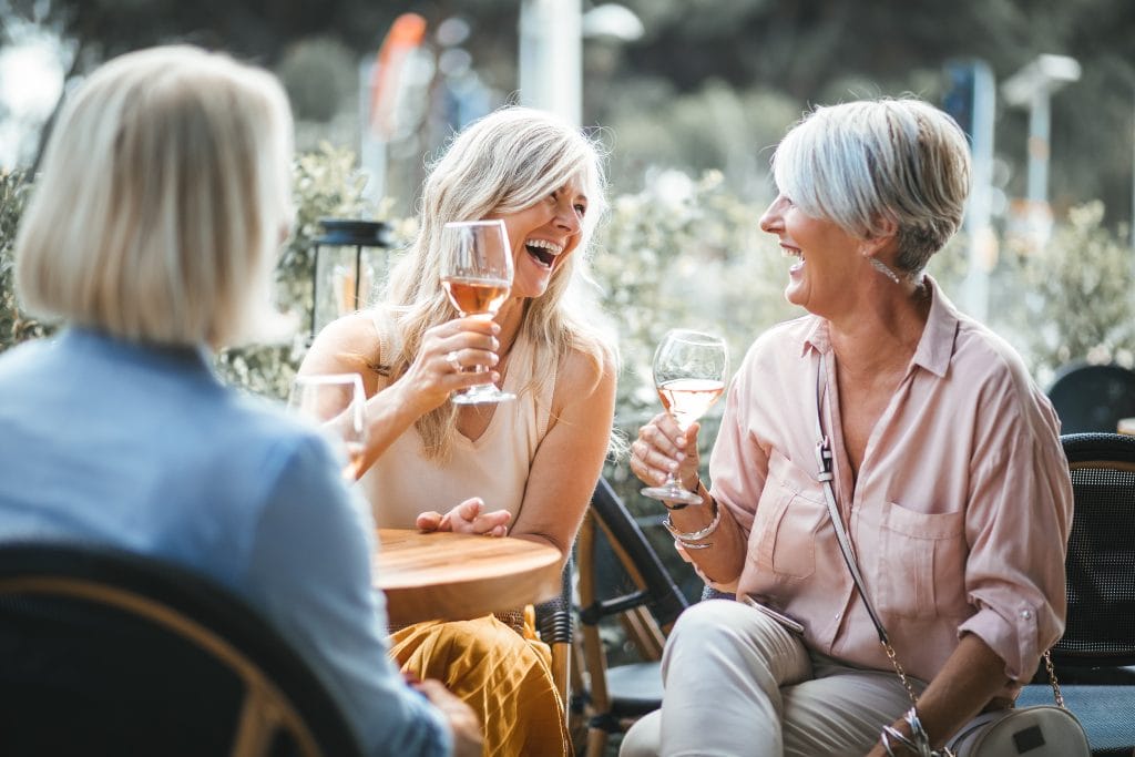 Mature women enjoying a glass of wine, having fun and laughing together at city restaurant